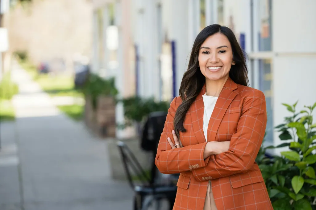Annalisa Perea, a 3rd generation Central Valley leader, smiling confidently with her arms crossed in an orange plaid blazer.
