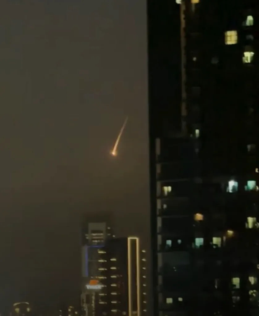Missile descending from the sky over a city at night.