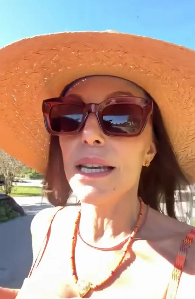 Bethenny Frankel wearing an orange sunhat and sunglasses.