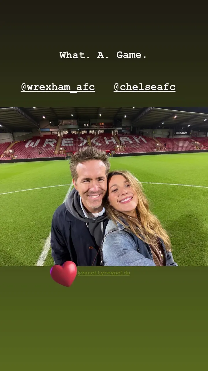 Blake Lively and Ryan Reynolds taking a selfie on a soccer field after a Wrexham vs. Chelsea match.
