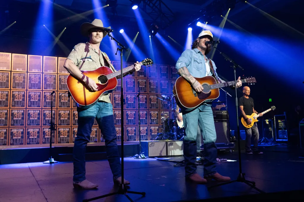 Brian Kelley and Tyler Hubbard of Florida Georgia Line perform on stage with guitars.