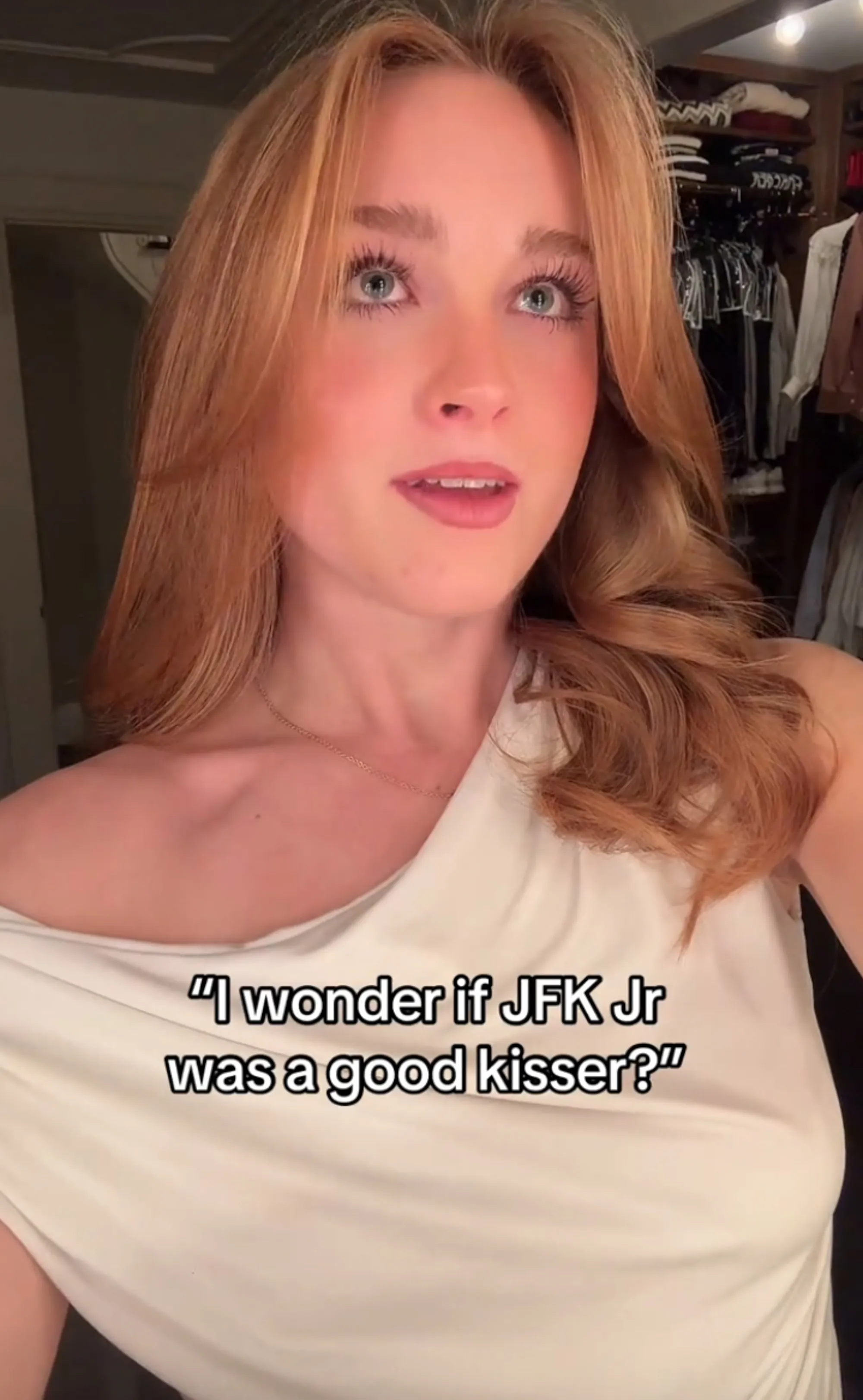 A woman with long light brown hair and a white top looking up with the text 