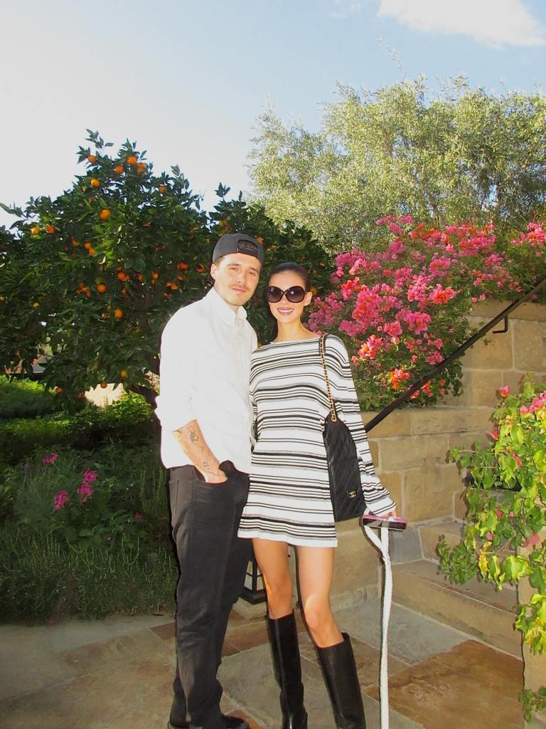 Brooklyn Beckham and Nicola Peltz standing together in a garden.