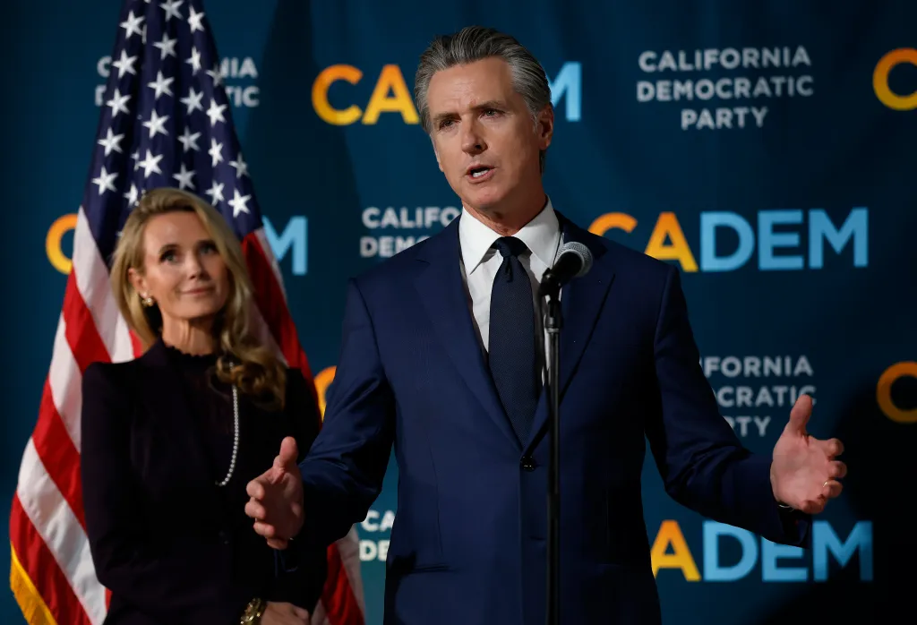 California Gov. Gavin Newsom speaks at an election night gathering as his wife Jennifer Siebel Newsom looks on.