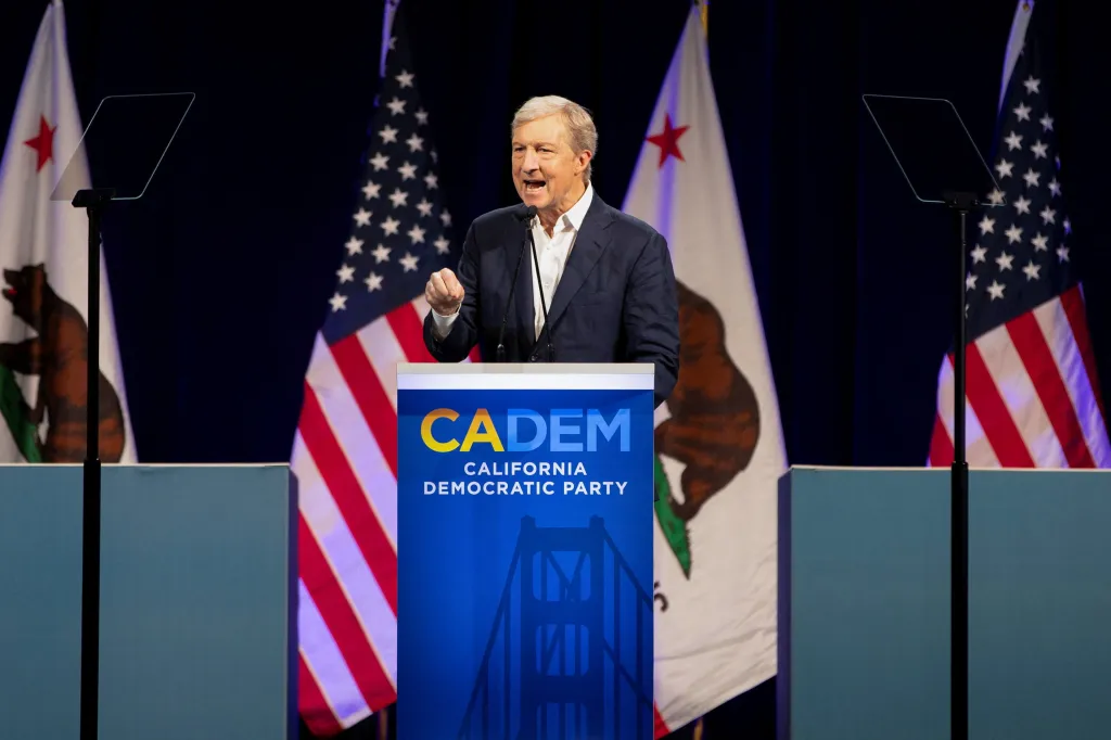 Tom Steyer speaking at the California Democratic Convention in front of American and Californian flags.