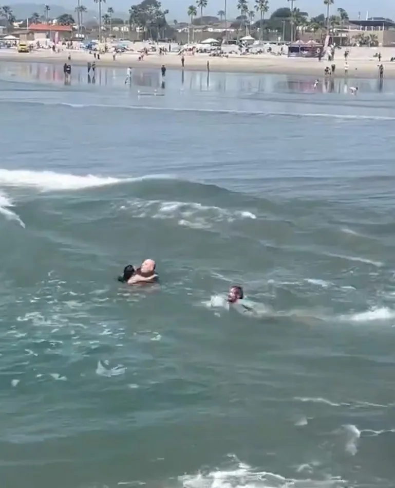 A surf instructor rescuing a young girl from drowning in the ocean.