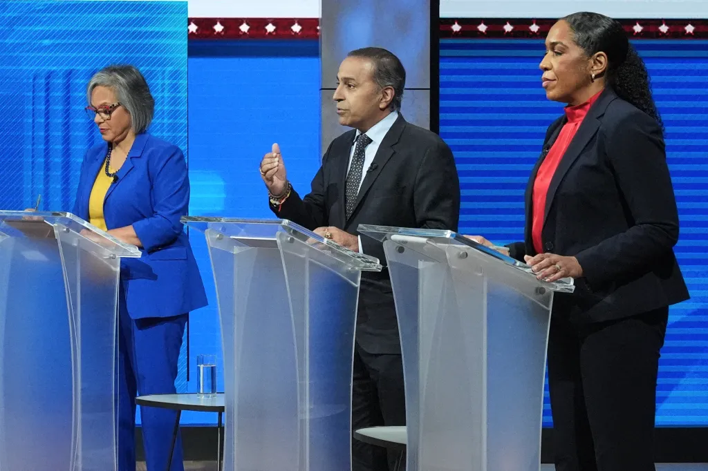 Raja Krishnamoorthi speaks at a debate with Robin Kelly and Juliana Stratton listening.