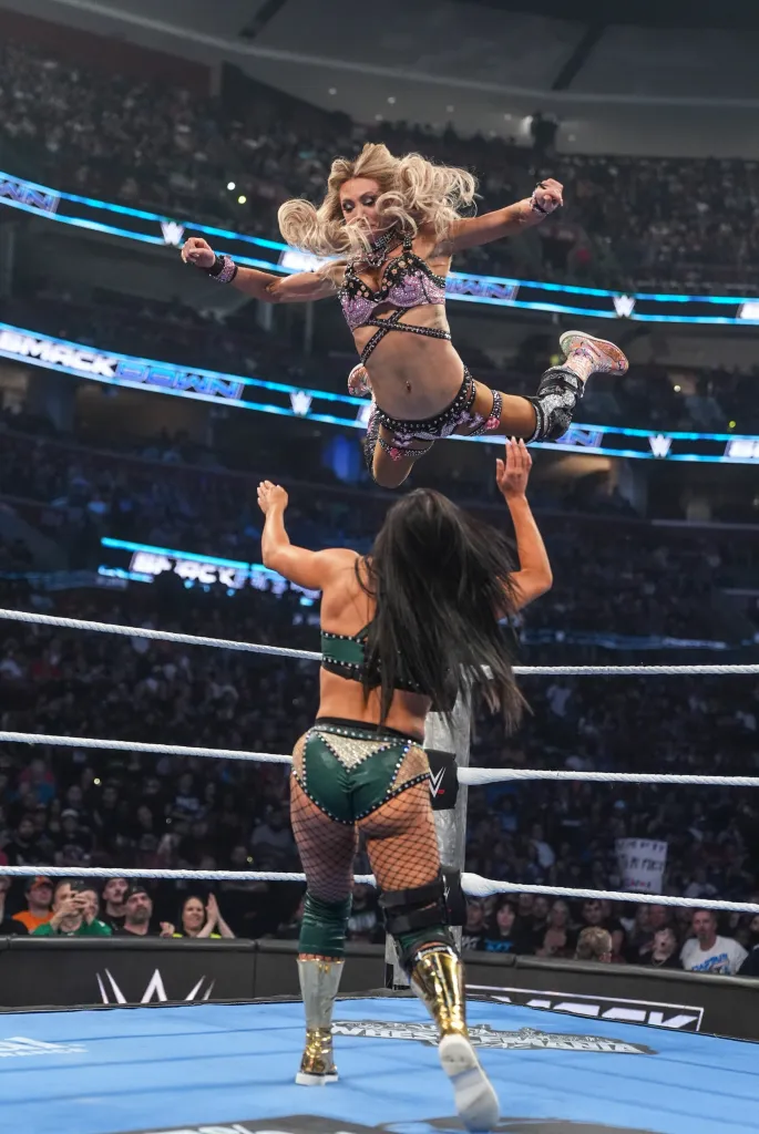 Charlotte Flair in mid-air above Kiana James during a wrestling match.
