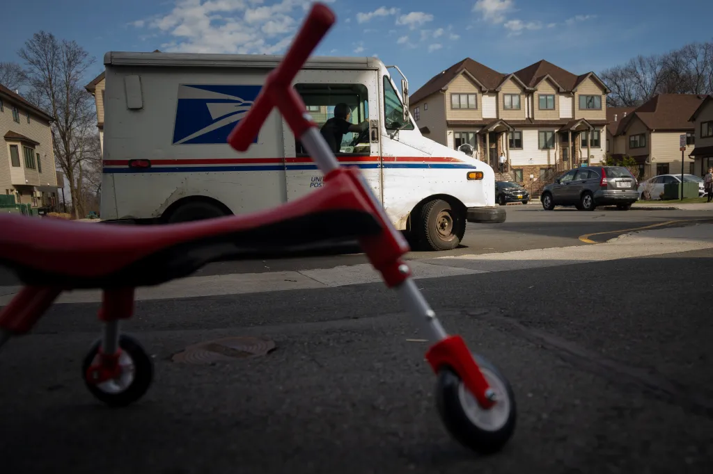 mail truck with a child's scooter in the foreground