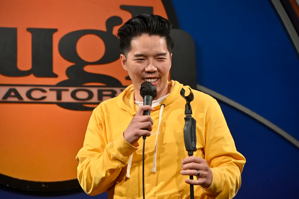 Comedian Alex Duong performing with a microphone at the Laugh Factory.