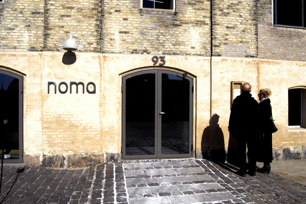 Two visitors standing outside the Noma two Michelin star restaurant in Copenhagen, Denmark.