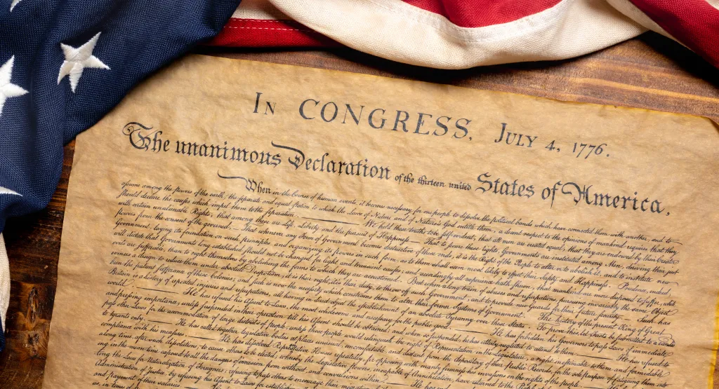 A copy of the United States Declaration of Independence with a vintage American flag.