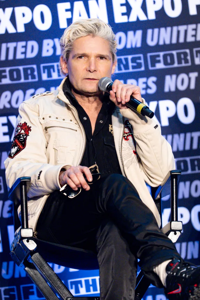 Corey Feldman speaking on stage with a microphone in his hand.