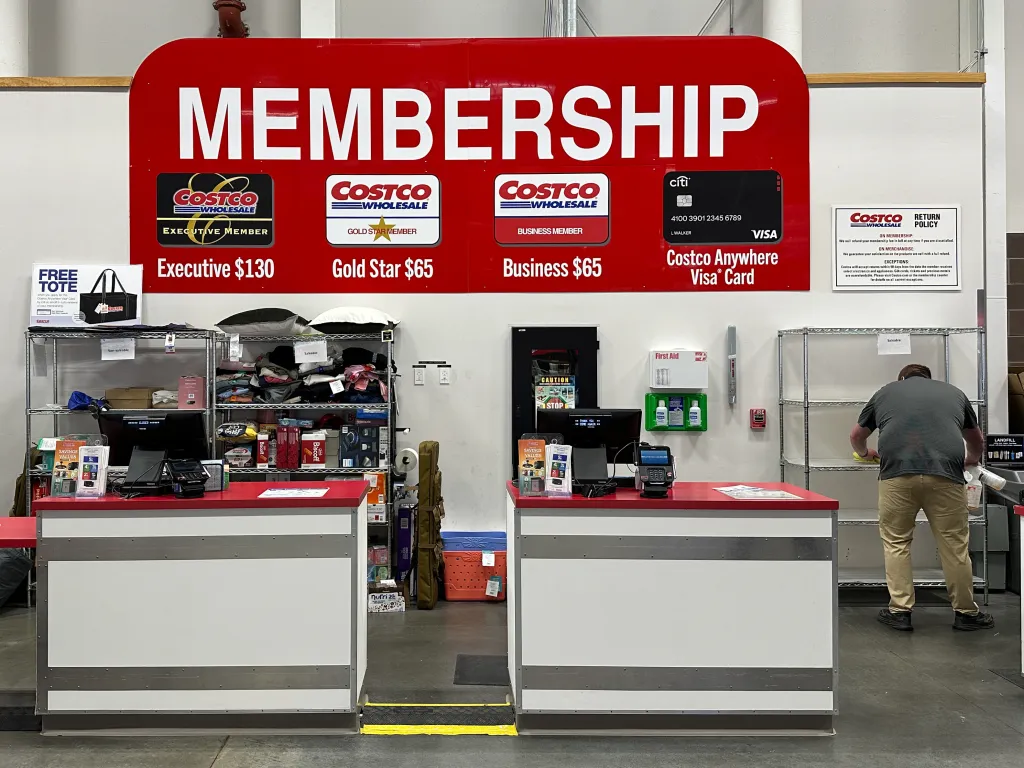 A Costco membership counter with a sign displaying membership options.