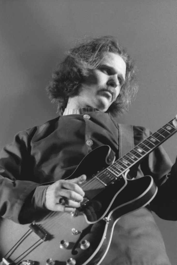 Country Joe McDonald playing an electric guitar during a live performance.