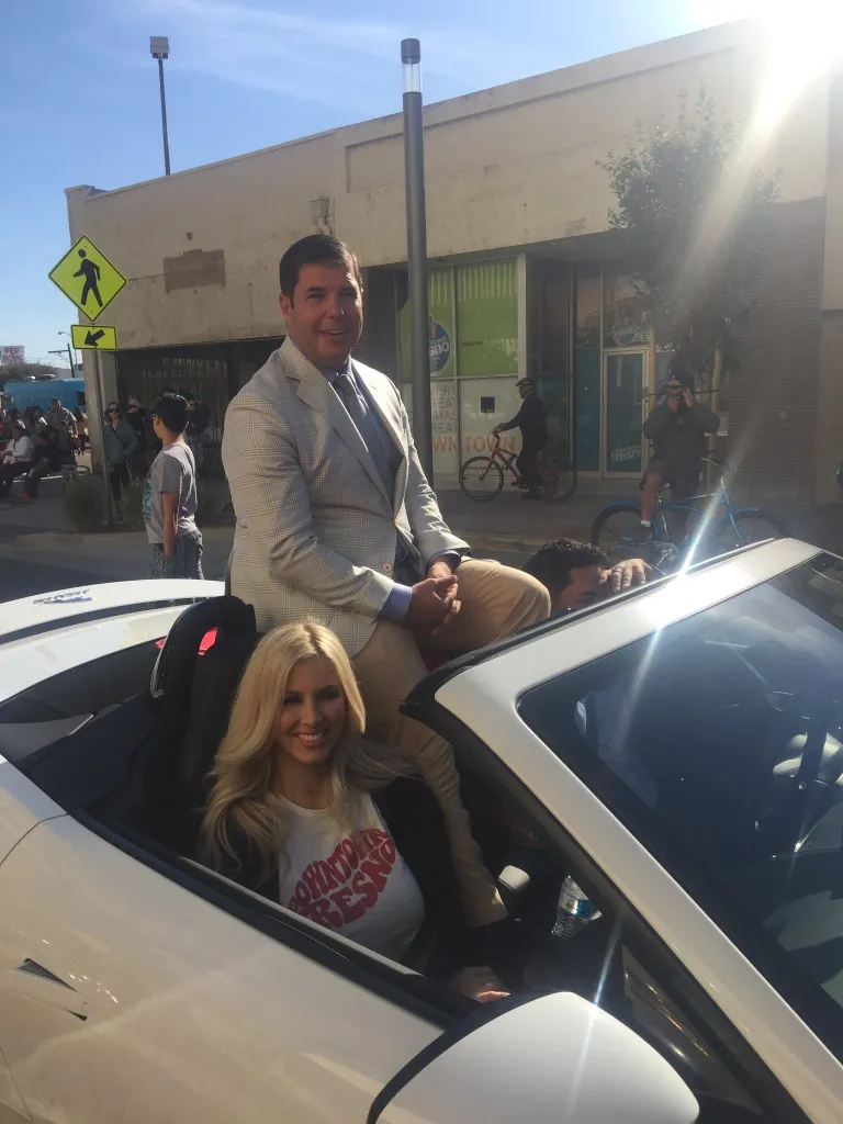 Joaquin Arambula seated on the back of a convertible, with Elizabeth Arambula smiling in the driver's seat.