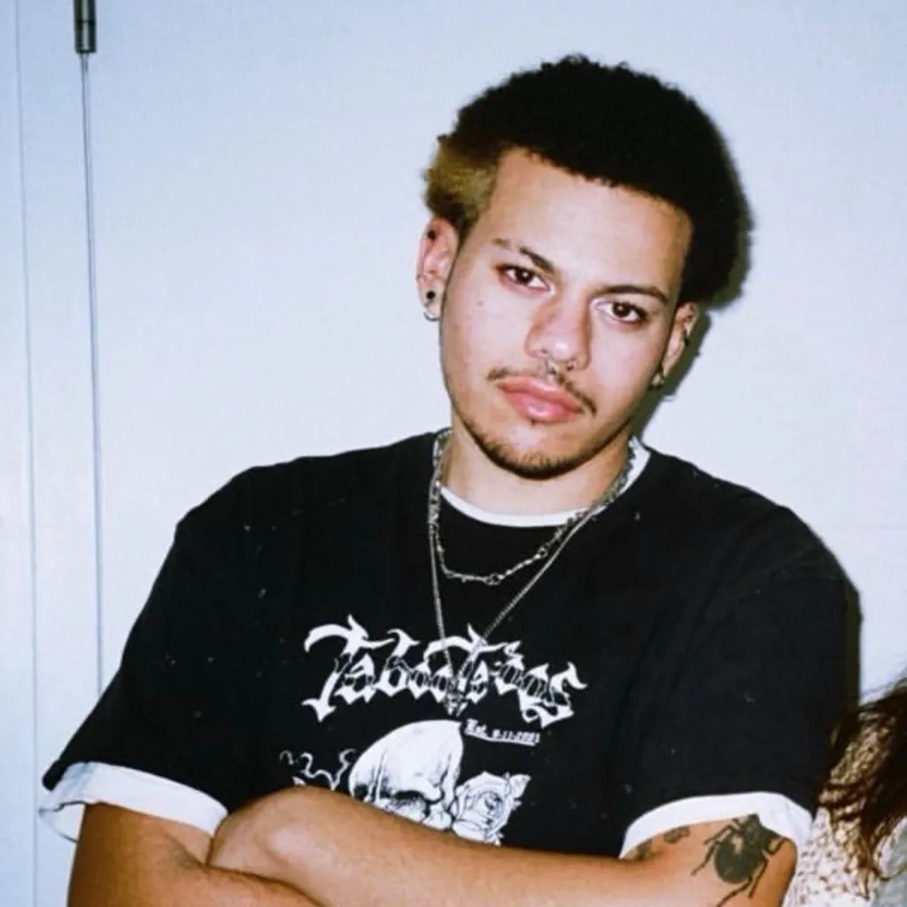 A photo of a young man against a wall.