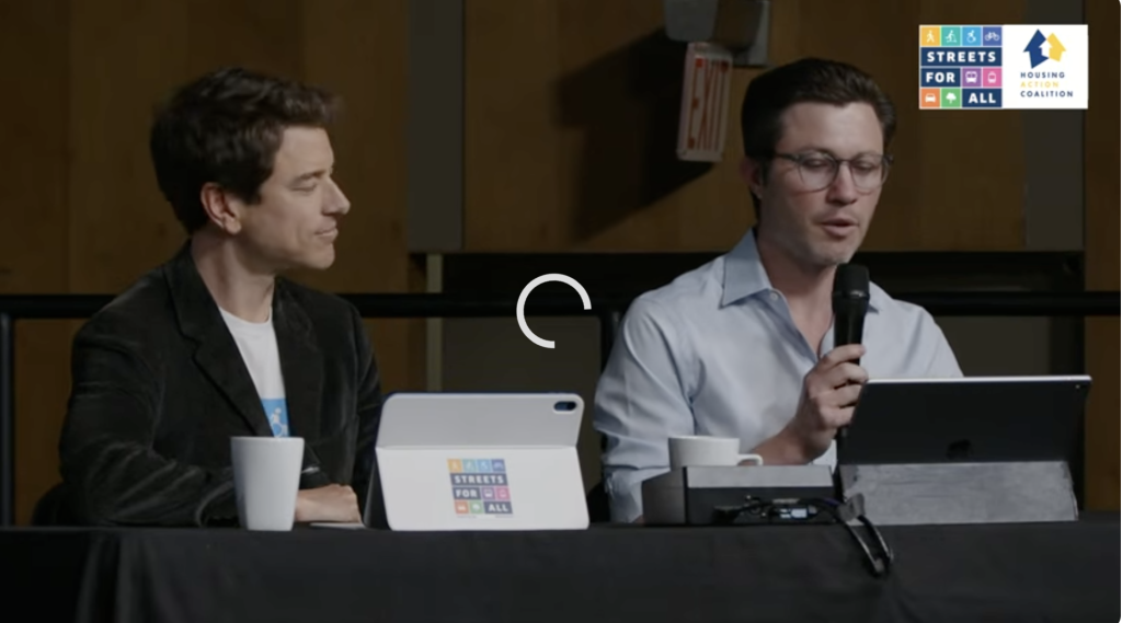Two men at a Los Angeles Mayoral debate, with the man on the right speaking into a microphone.