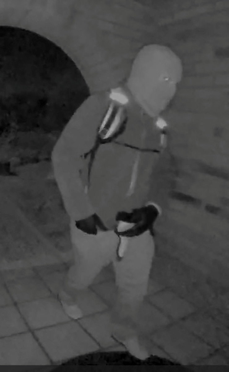 Security camera image of an armed individual in a ski mask.