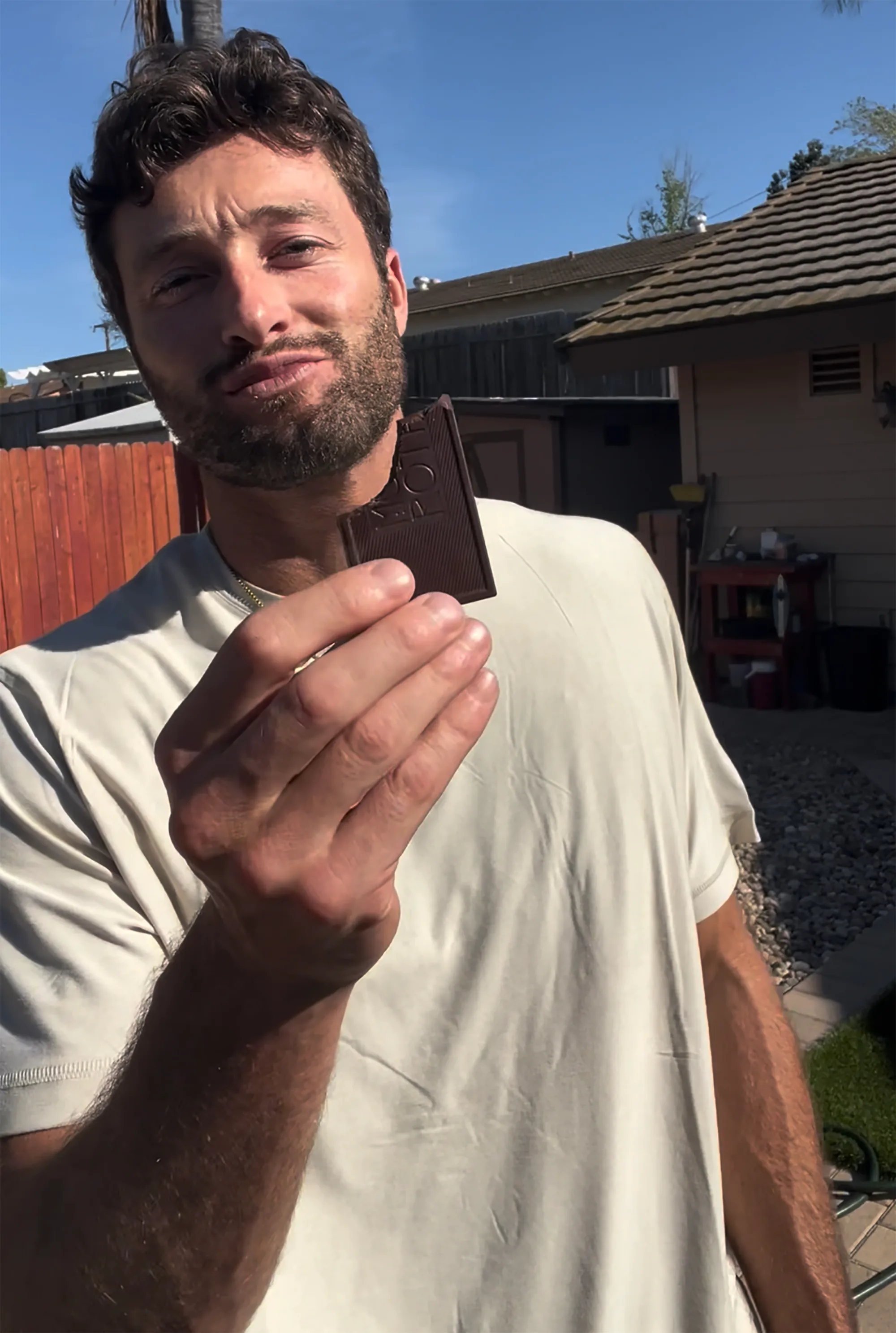 A man holding a piece of chocolate up to the camera.