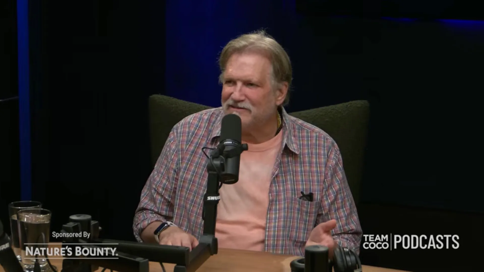 Drew Carey speaking into a microphone on Team Coco Podcasts.