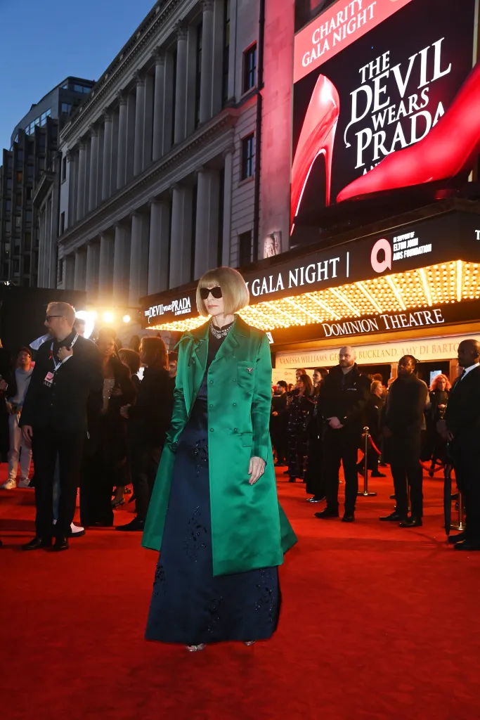 Anna Wintour, in a green coat navy blue gown and sunglasses, walking the red carpet at the world premiere of 