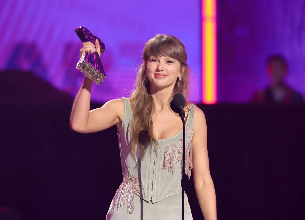 Taylor Swift smiling and holding the Pop Album of the Year award at the 2026 iHeartRadio Music Awards.