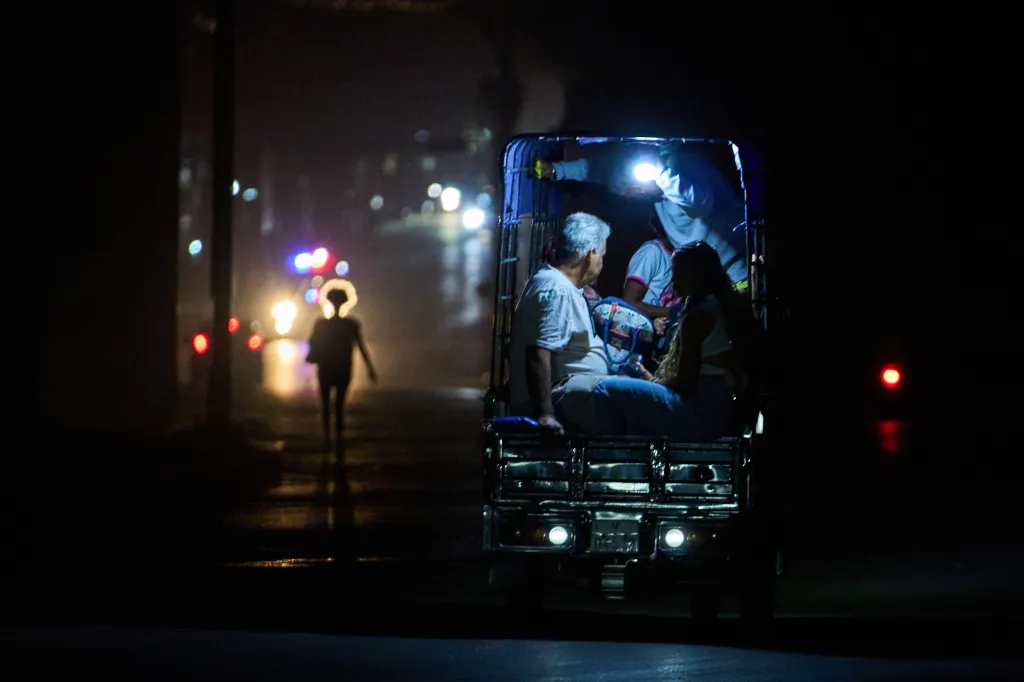 People ride in the back of an electric tricycle during a blackout.