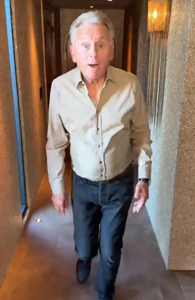 Pat Sajak looking surprised as he walks towards the camera in a hallway.