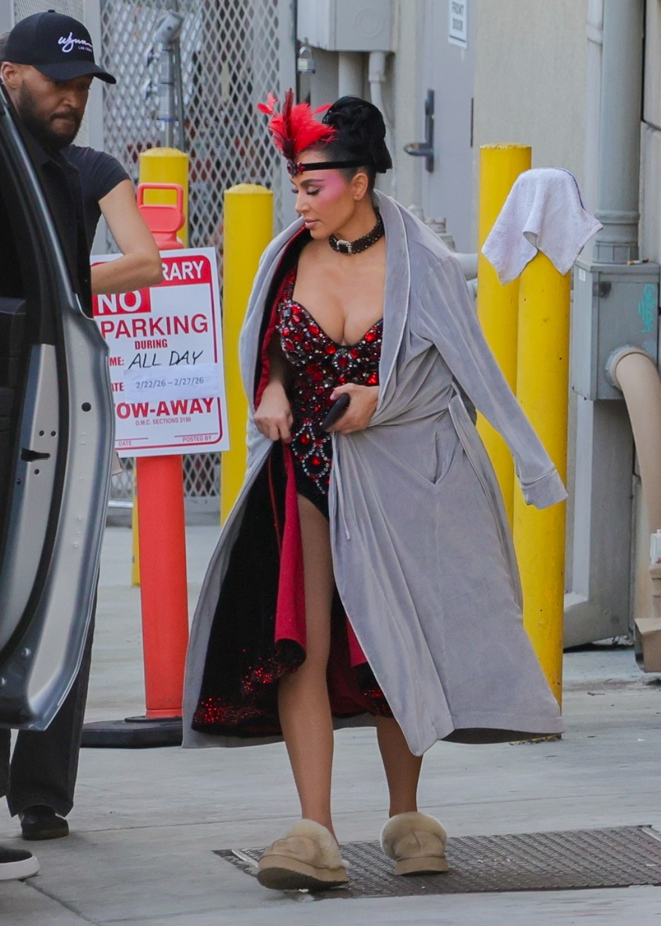 Kim Kardashian wearing a showgirl costume and a gray robe on the set of 