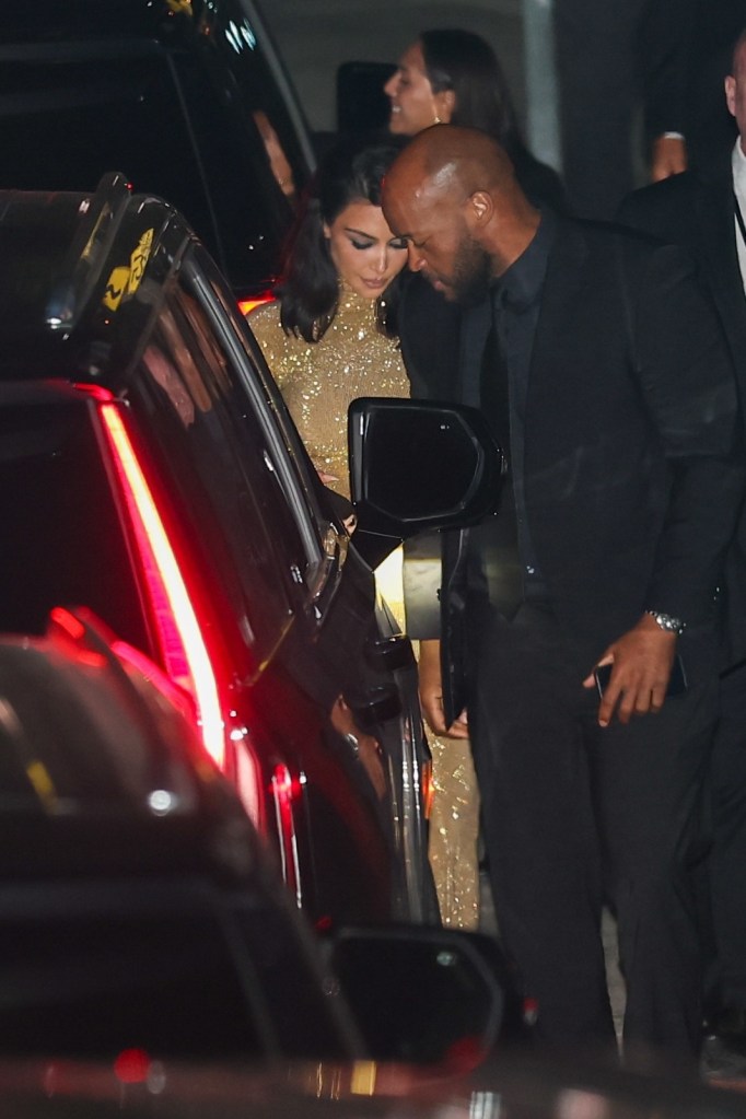 Kim Kardashian exiting a black car, wearing a sparkling gold dress, with a man in a dark suit by her side.