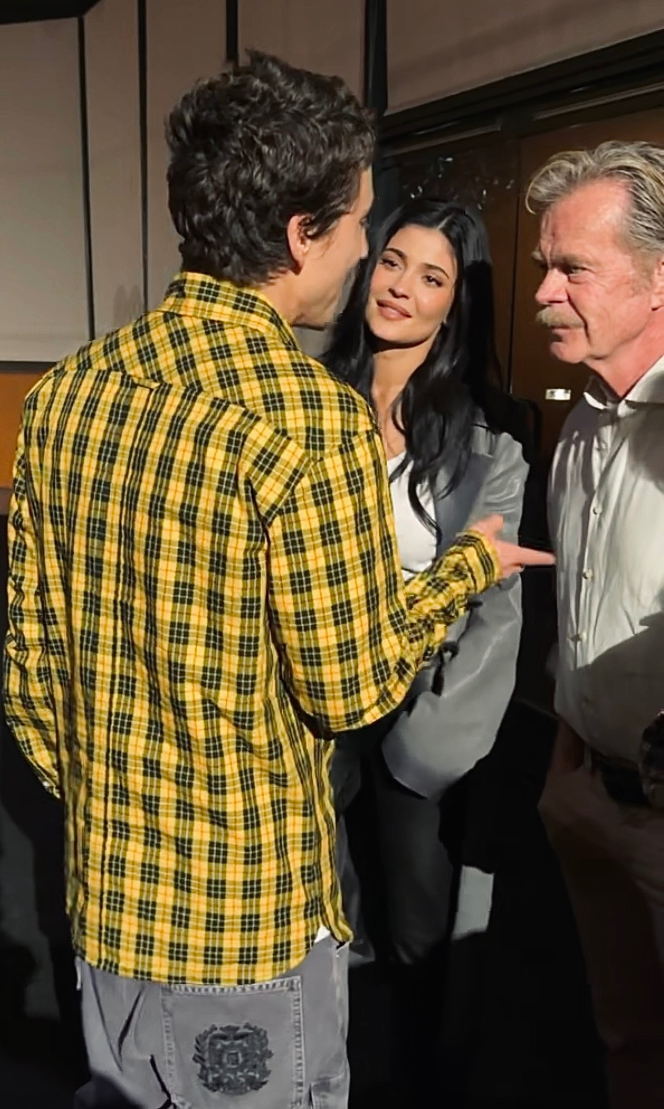 Kylie Jenner smiling at Timothée Chalamet as William H. Macy looks on.