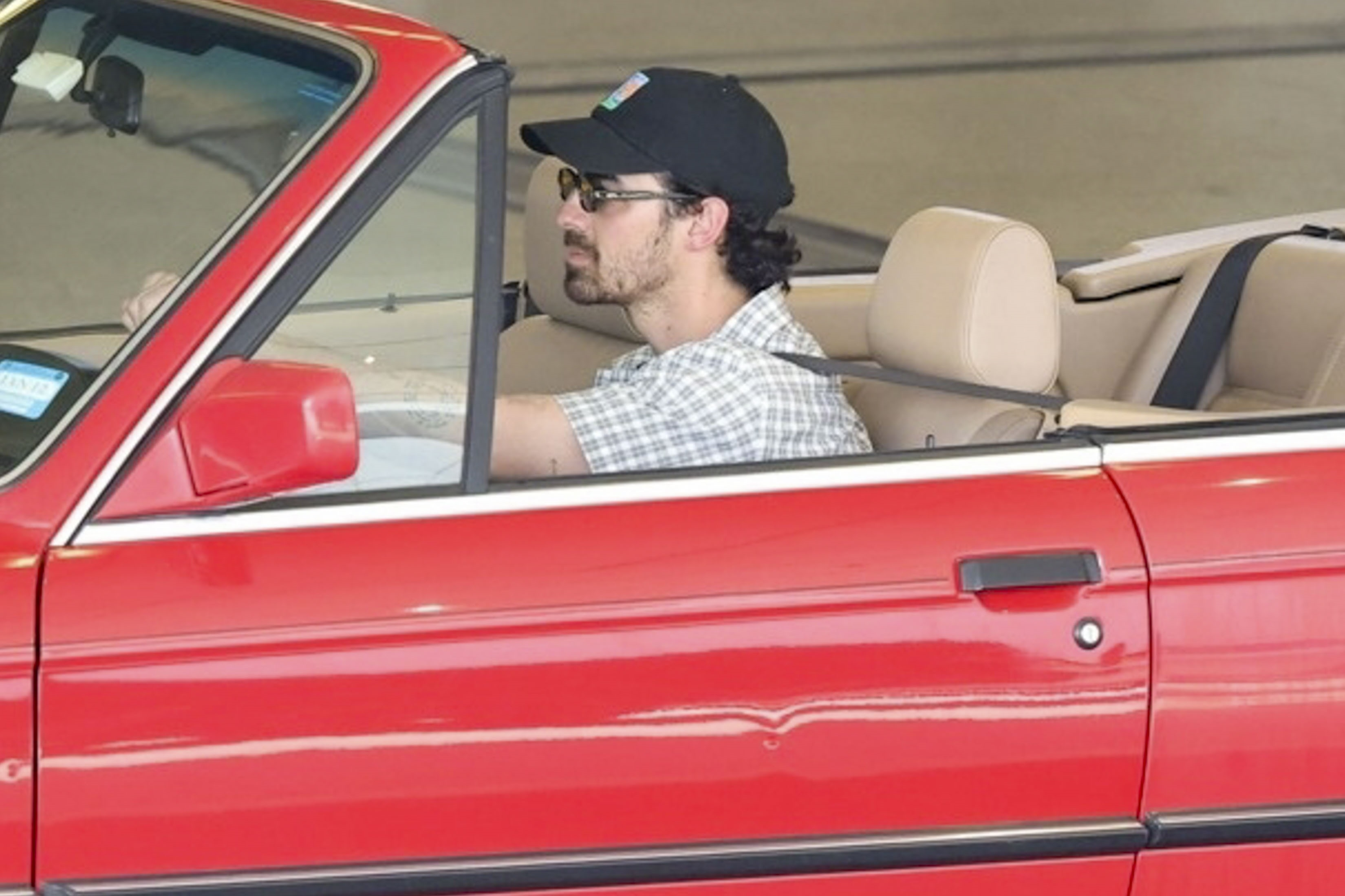 Joe Jonas driving a red BMW convertible.