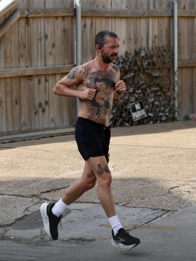 Shia LaBeouf jogging shirtless with visible tattoos in New Orleans.