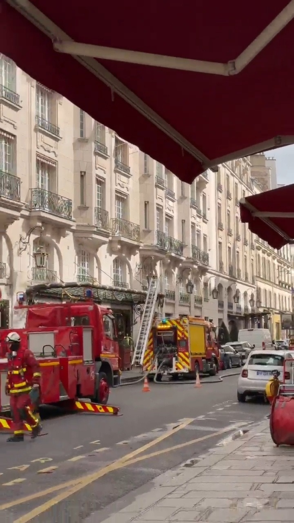 Fire trucks and firefighters outside a large hotel, after a fire required evacuation of the building.