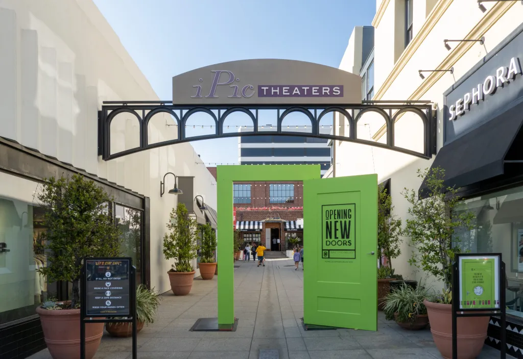 Exterior view of iPic Theaters signage with a green 