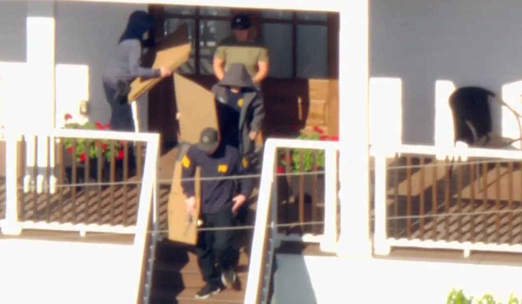 FBI agents leaving a home during a raid.