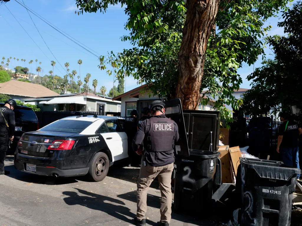 Police officers on a residential street during an arrest operation.