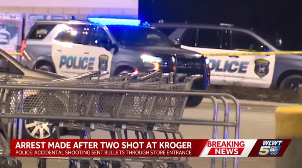 Police vehicles with flashing blue lights at a Kroger store, with shopping carts in the foreground.