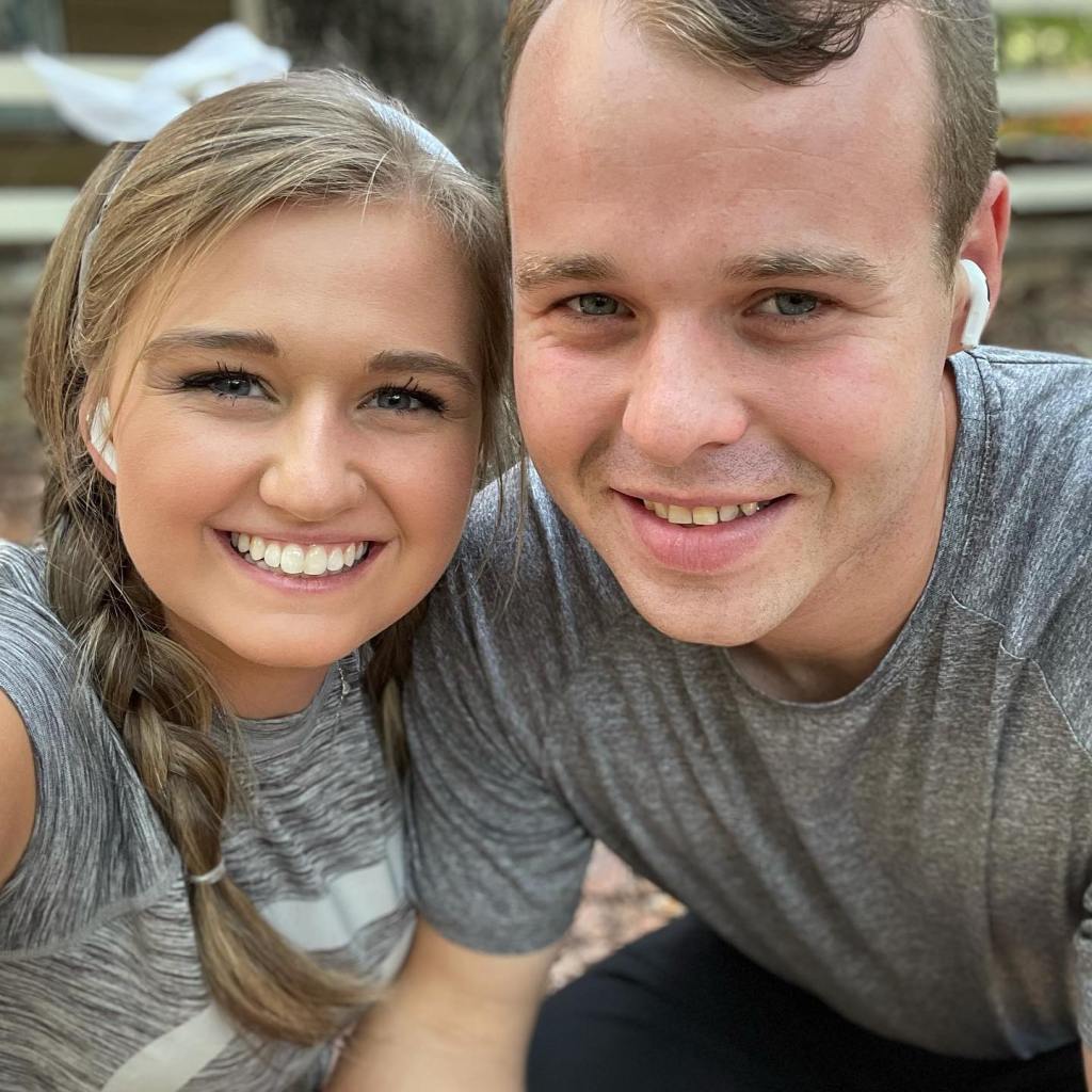 Joseph and Kendra Duggar pose for a selfie, both wearing grey athletic shirts and white earbuds.