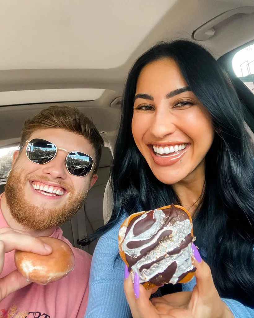 A selfie of a couple holding donuts. 