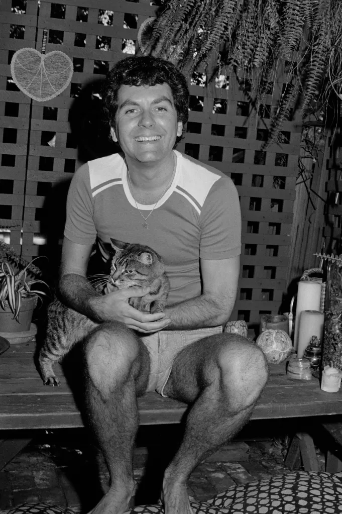 French costume designer Jean-Pierre Dorleac holding a cat in the garden of his Los Angeles home.