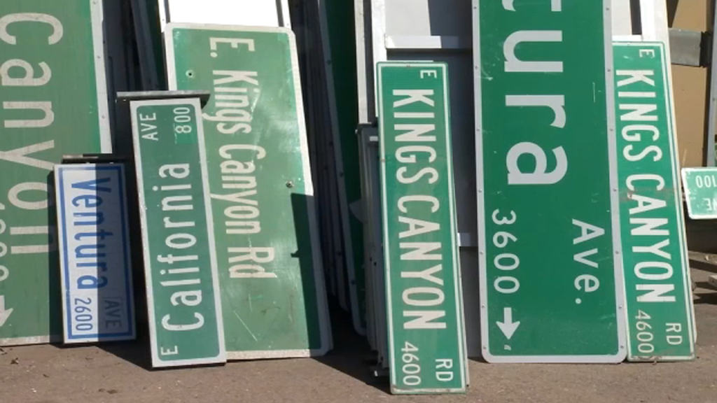 A collection of street signs, mostly green, including 