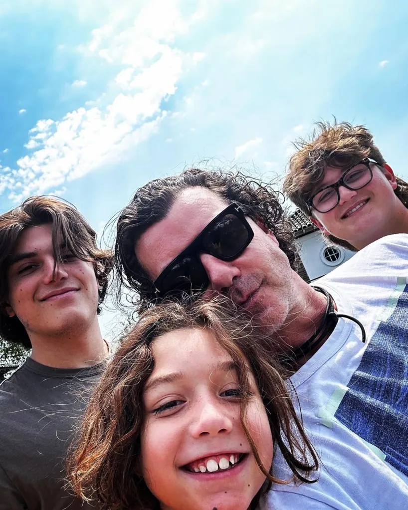 Gavin Rossdale and his three sons in a close-up selfie under a blue sky.