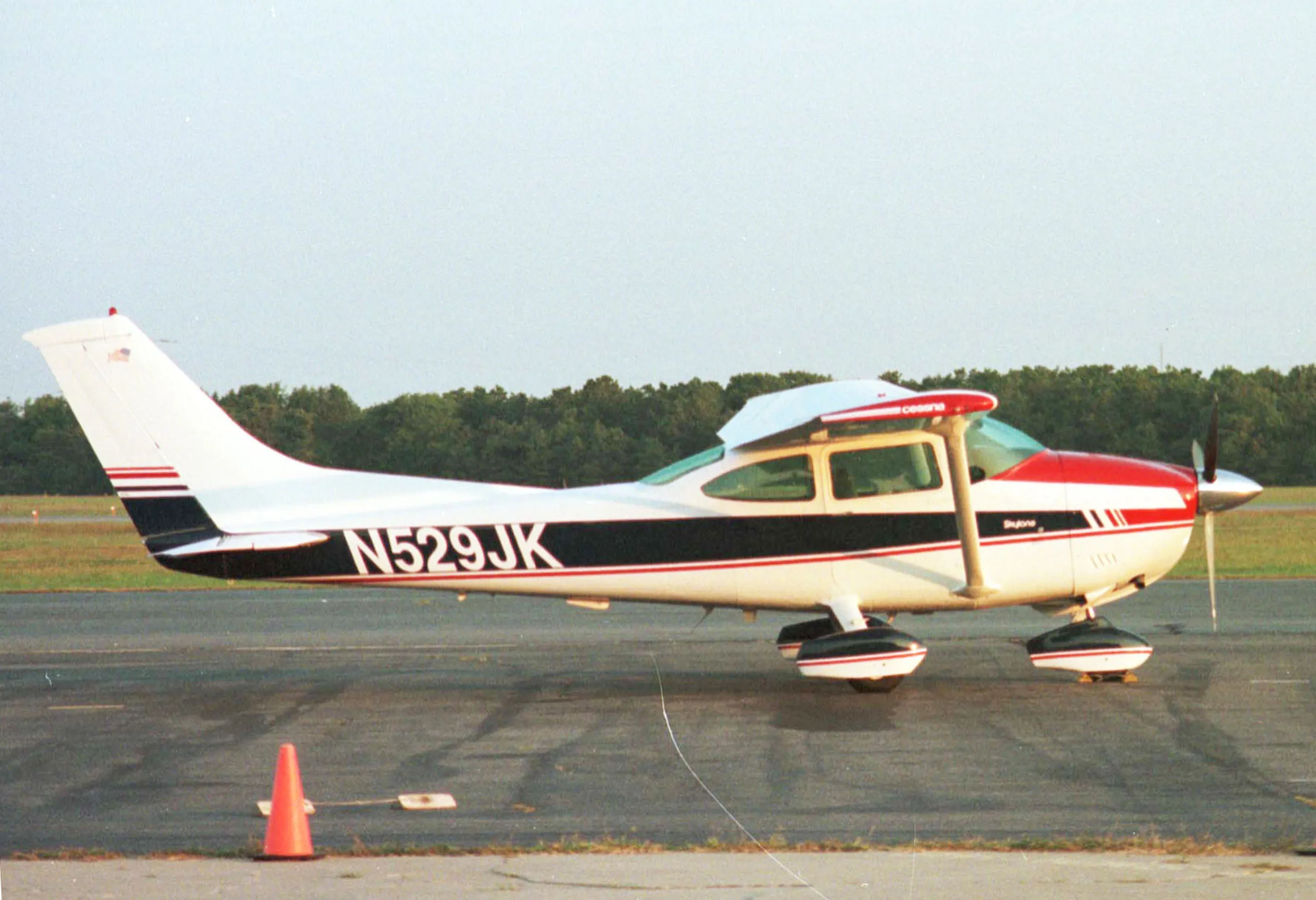 John Kennedy Jr.'s red, white, and blue Cessna Skylane airplane on an airfield.