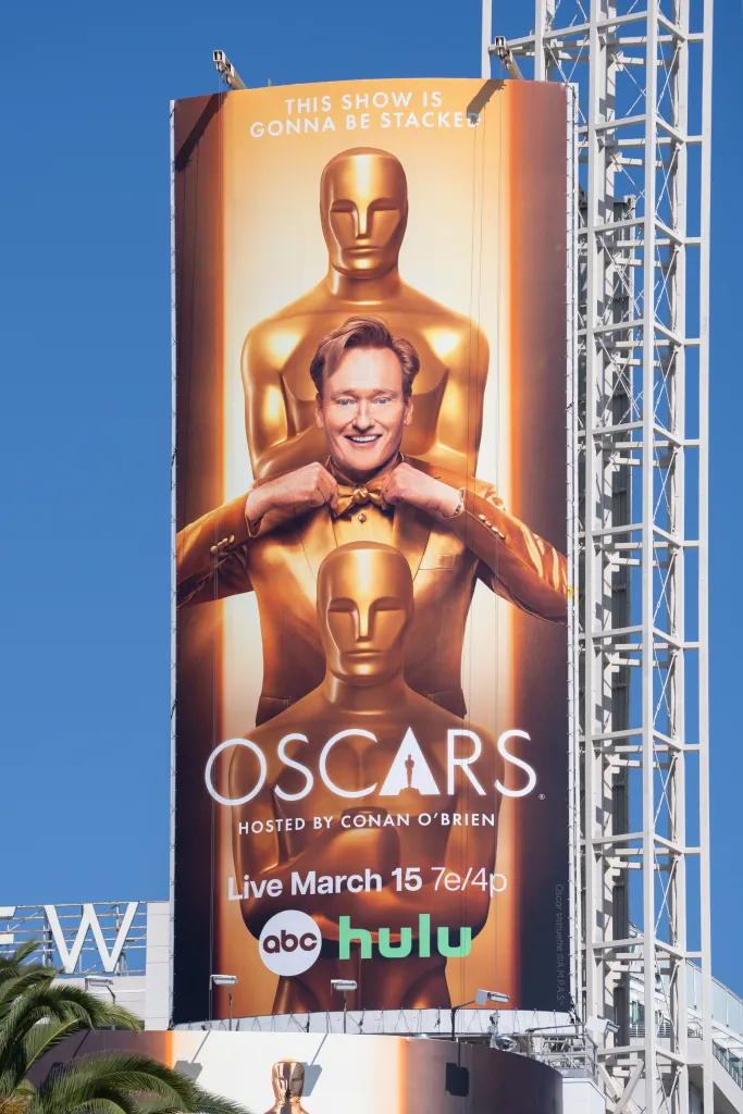 Billboard for the Oscars, showing Conan O'Brien in a gold suit, standing in front of an Oscar statuette.