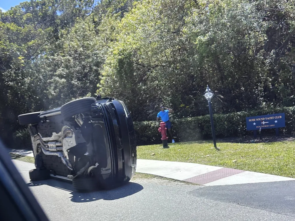 Tiger Woods stands by his overturned vehicle near a 