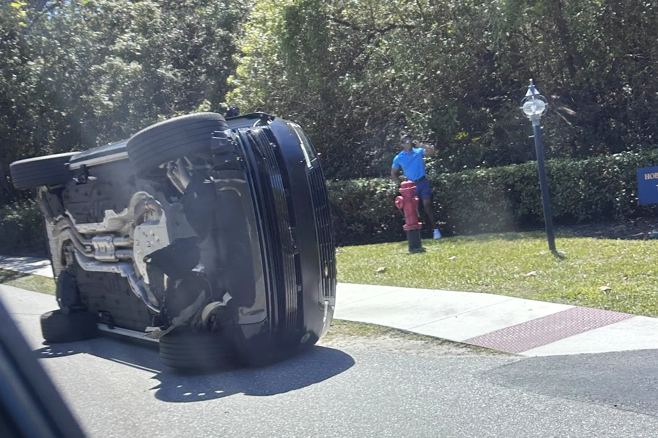 Golfer Tiger Woods standing by his overturned vehicle after a crash.