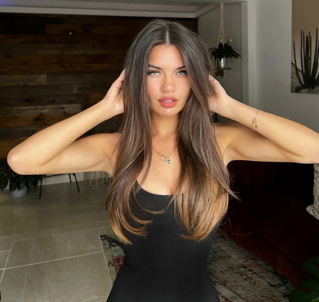 Grace Lilly in a black top, with hands in her hair.