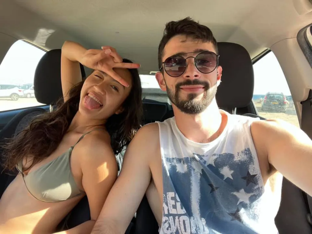 The couple smiles in a selfie in a car. 